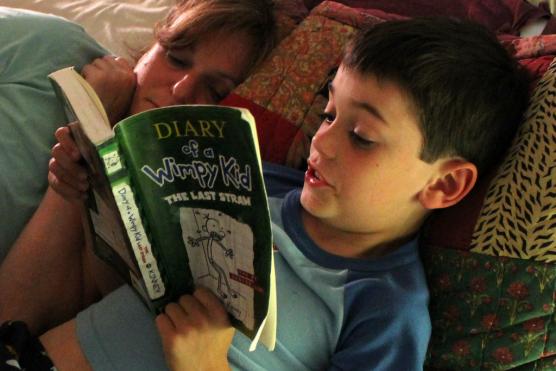 A child reads a book with his mother
